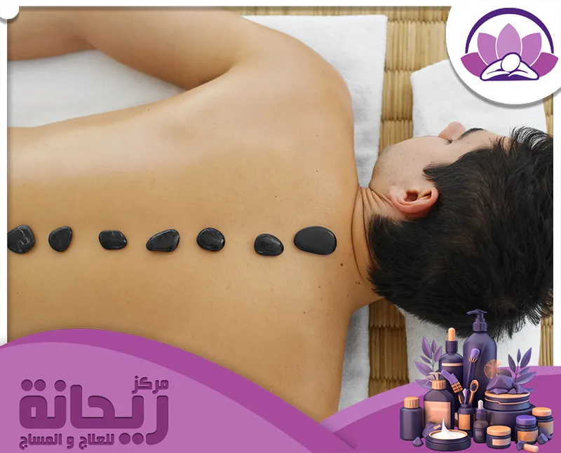 رجل مستلقٍ على السرير مع أحجار على ظهره، فلبيني مساج الاحساء. 